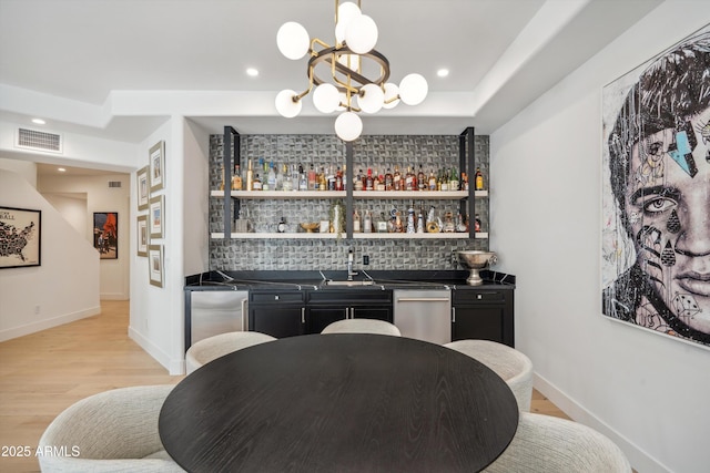 bar with an inviting chandelier, appliances with stainless steel finishes, sink, and decorative backsplash