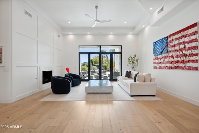 living room featuring a towering ceiling, ceiling fan, and light hardwood / wood-style flooring