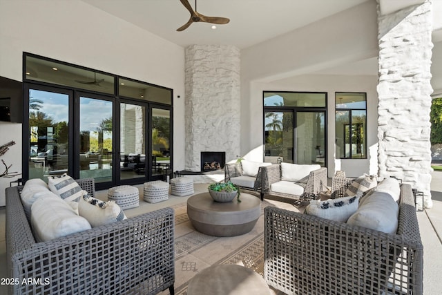 view of patio featuring ceiling fan and an outdoor living space with a fireplace