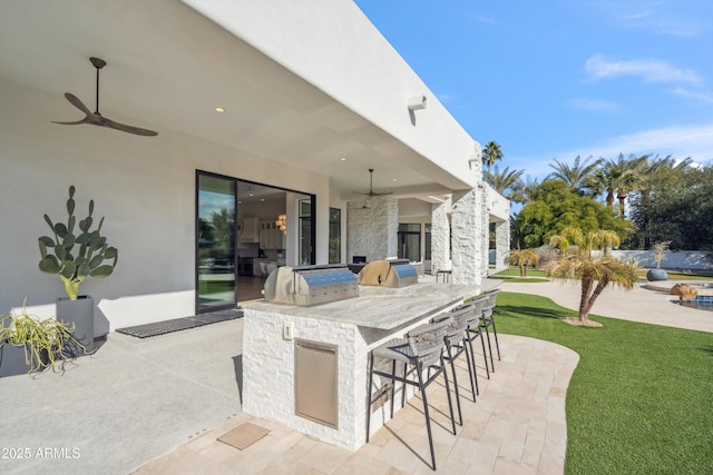 view of patio featuring ceiling fan, area for grilling, and an outdoor bar