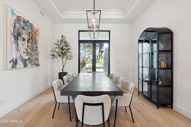 dining space featuring french doors, ornamental molding, light hardwood / wood-style floors, and a tray ceiling