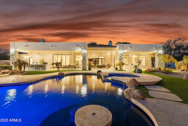 pool at dusk featuring an in ground hot tub, ceiling fan, and a patio