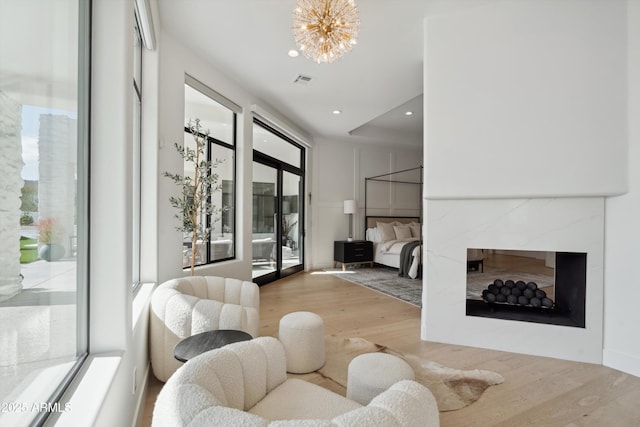 living room featuring a premium fireplace, plenty of natural light, a chandelier, and light hardwood / wood-style flooring