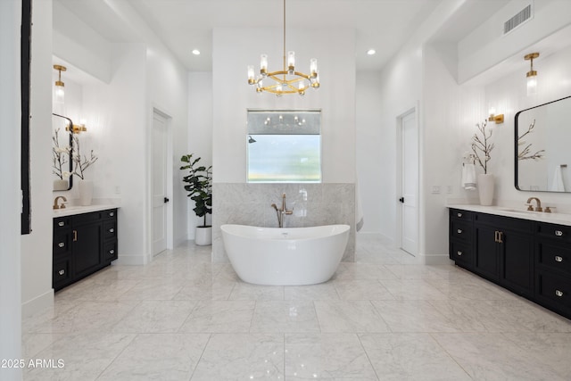 bathroom featuring a chandelier, vanity, a bathing tub, and tile walls