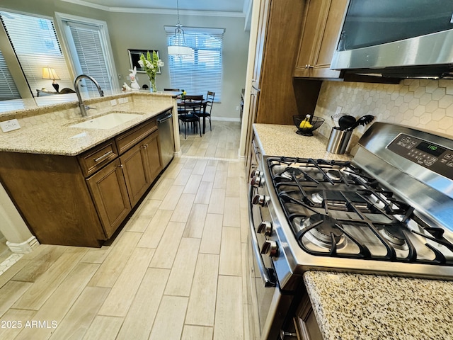 kitchen featuring a sink, appliances with stainless steel finishes, crown molding, baseboards, and light wood-style floors