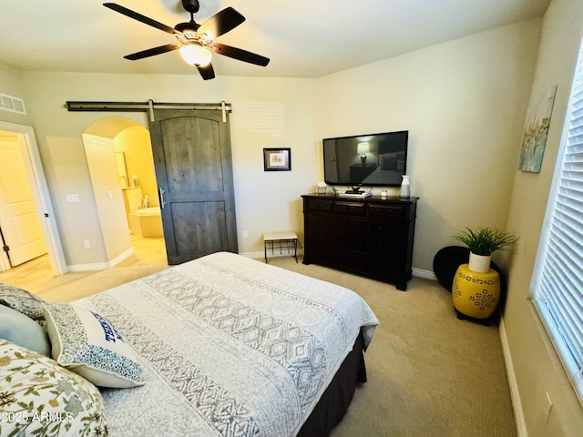 bedroom featuring light carpet, a barn door, visible vents, and arched walkways