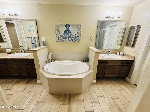 bathroom with a sink, a garden tub, and wood finished floors