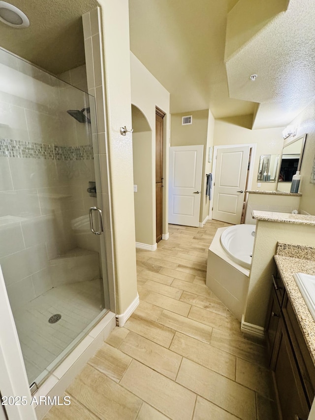 bathroom featuring a garden tub, a stall shower, visible vents, baseboards, and vanity