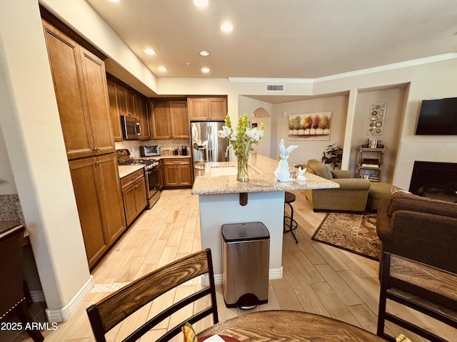 kitchen with a kitchen bar, stainless steel appliances, open floor plan, visible vents, and a kitchen island