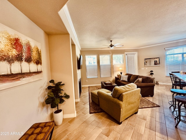 living area with a ceiling fan, ornamental molding, light wood-style flooring, and a textured ceiling