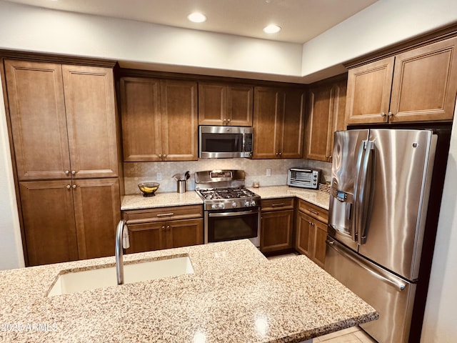 kitchen with a sink, a toaster, stainless steel appliances, light stone counters, and recessed lighting