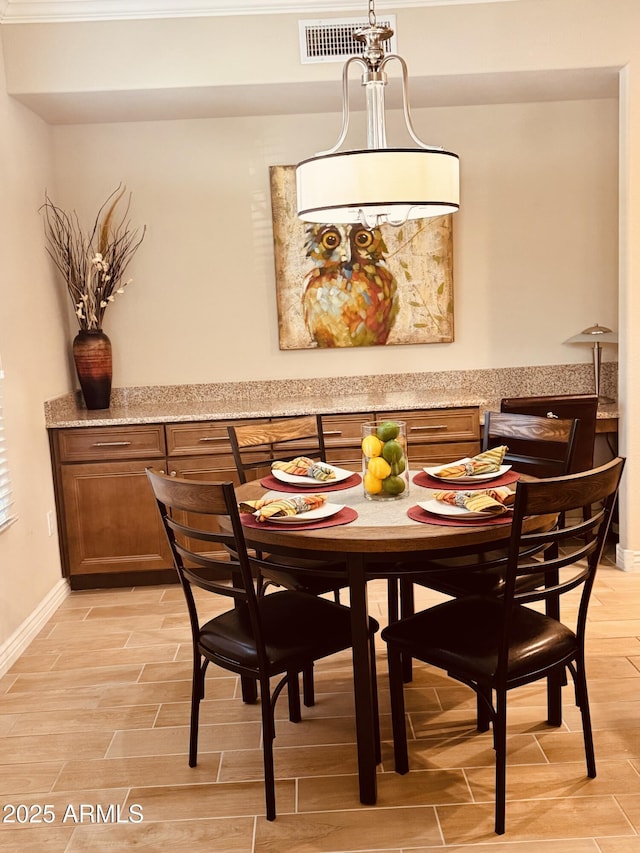 dining space featuring baseboards, visible vents, and wood finish floors