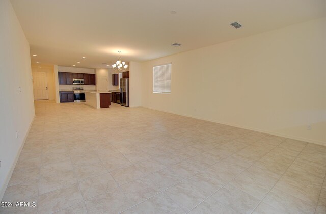 unfurnished living room featuring a notable chandelier and light tile patterned flooring