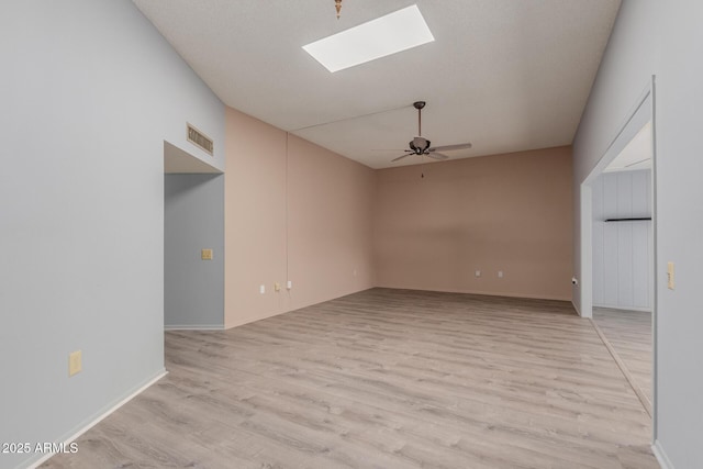 spare room with light hardwood / wood-style flooring, a skylight, and ceiling fan