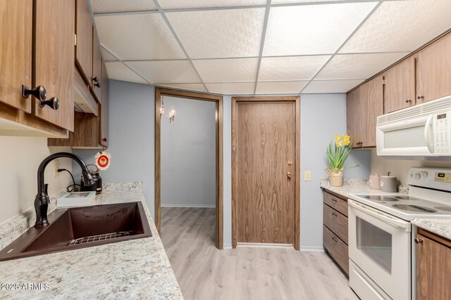 kitchen featuring sink, white appliances, a paneled ceiling, and light wood-type flooring