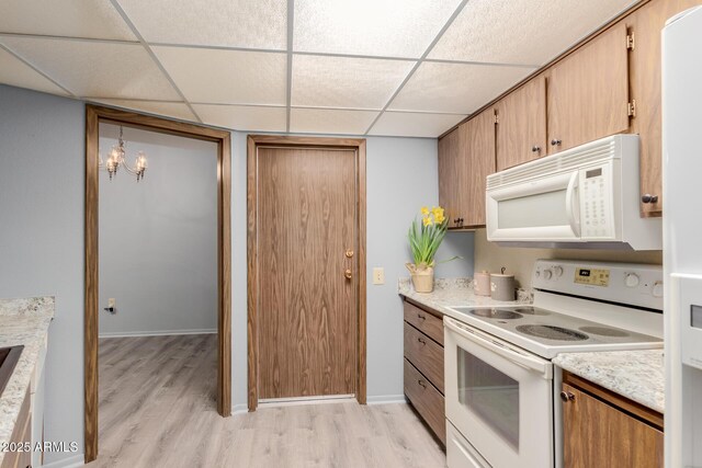 kitchen with white appliances, light hardwood / wood-style flooring, and a drop ceiling