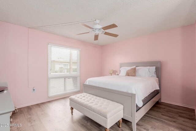 bedroom with hardwood / wood-style flooring, ceiling fan, and a textured ceiling