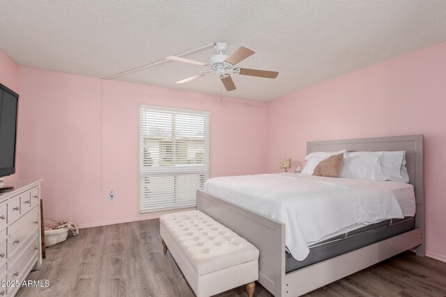 bedroom featuring ceiling fan, a textured ceiling, and light wood-type flooring