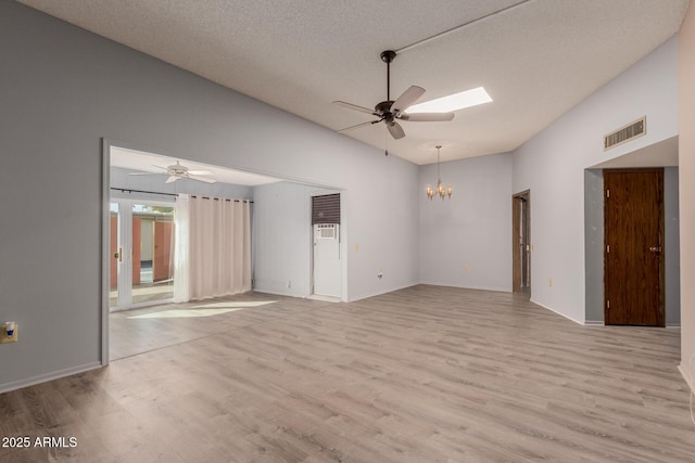 unfurnished room with lofted ceiling, ceiling fan with notable chandelier, a textured ceiling, and light wood-type flooring