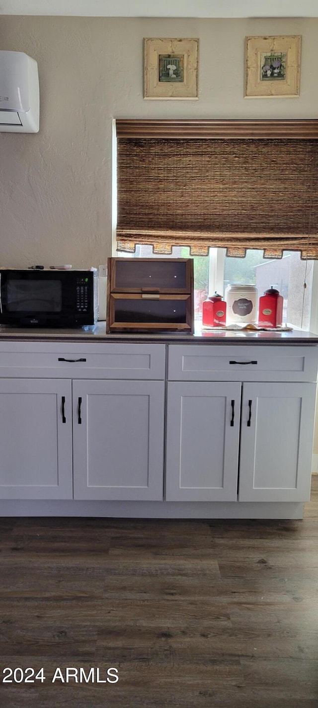 kitchen with white cabinets, a wall mounted air conditioner, and dark hardwood / wood-style floors