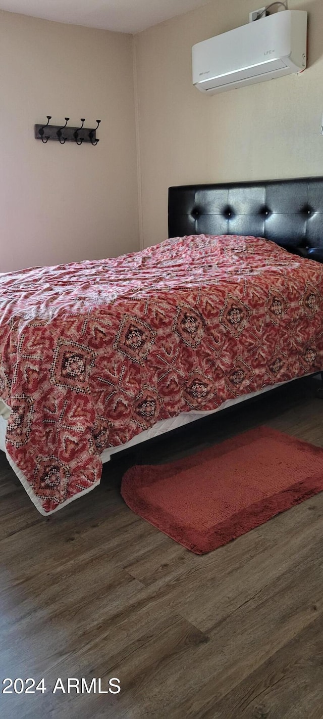 bedroom with a wall mounted AC and dark hardwood / wood-style floors