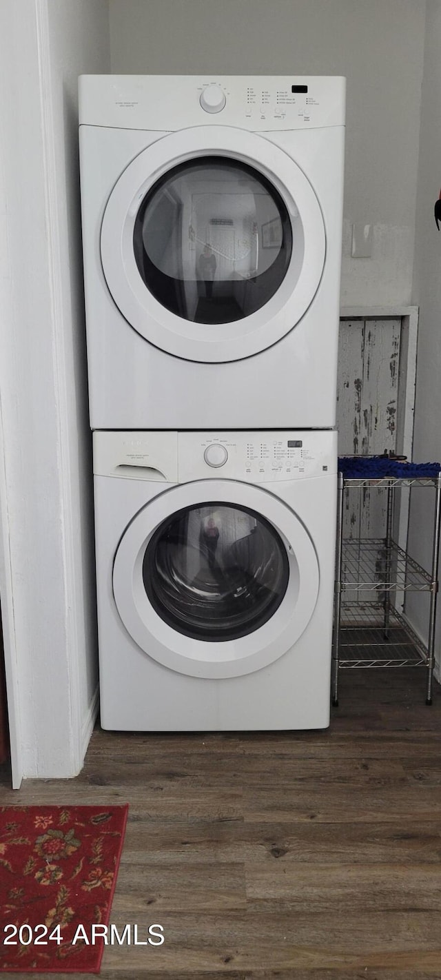 laundry room featuring dark wood-type flooring and stacked washing maching and dryer