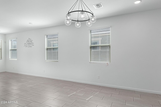 unfurnished room with a notable chandelier