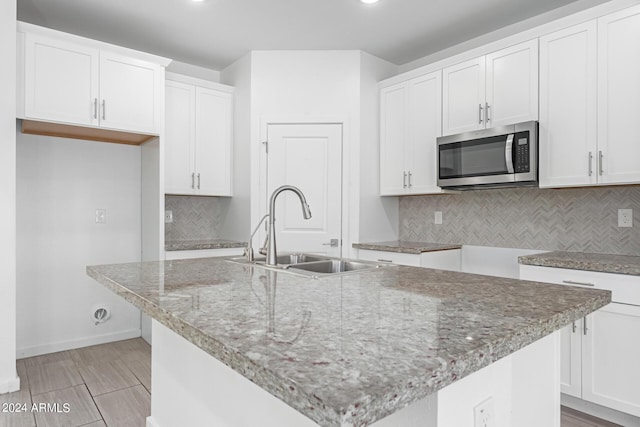 kitchen featuring sink, white cabinetry, and an island with sink