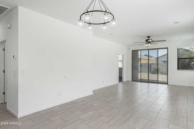 unfurnished room featuring ceiling fan with notable chandelier