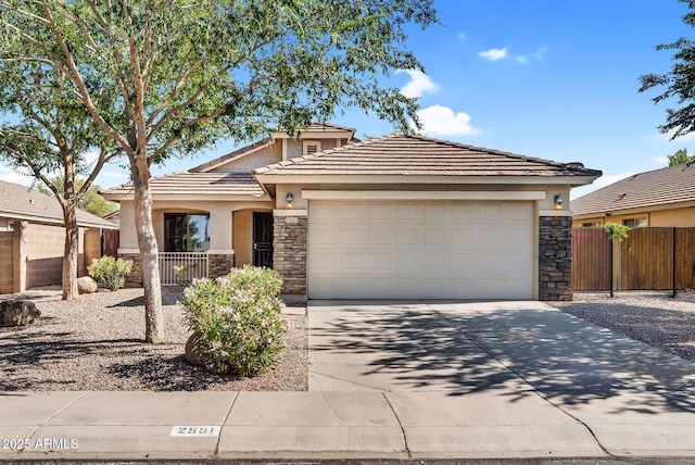view of front of property with stone siding, fence, concrete driveway, and an attached garage