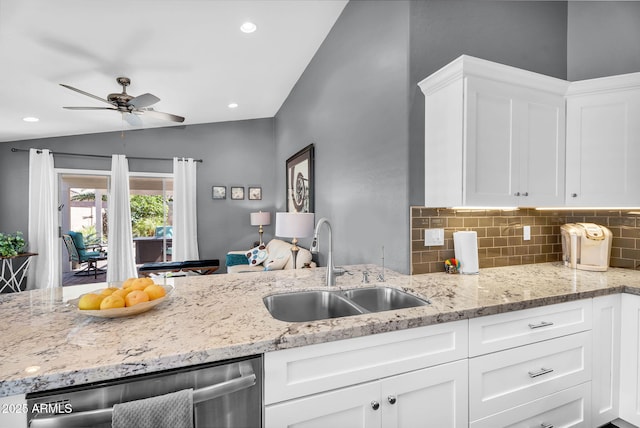 kitchen with dishwasher, a sink, backsplash, vaulted ceiling, and white cabinetry