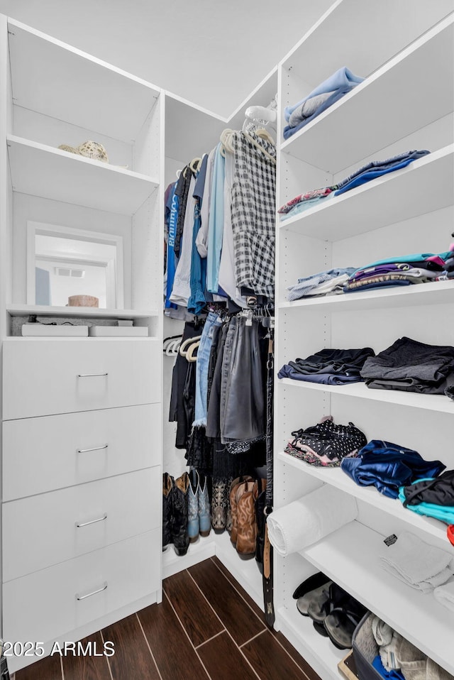 walk in closet with dark wood-style floors