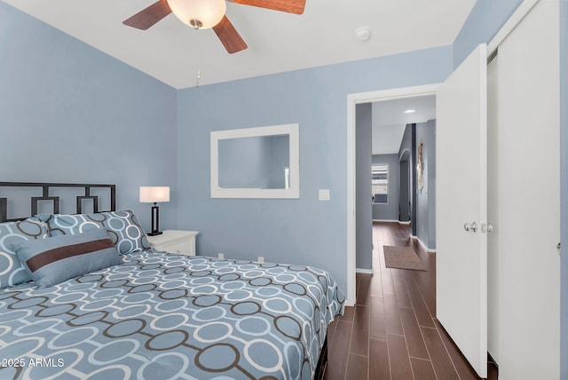 bedroom with dark wood-style floors, ceiling fan, and baseboards