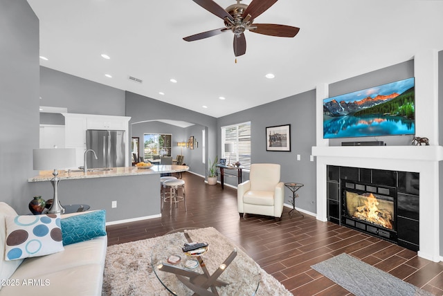 living room with lofted ceiling, arched walkways, dark wood-type flooring, recessed lighting, and baseboards