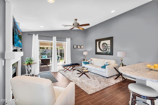 living area with vaulted ceiling, dark wood finished floors, ceiling fan, recessed lighting, and a large fireplace