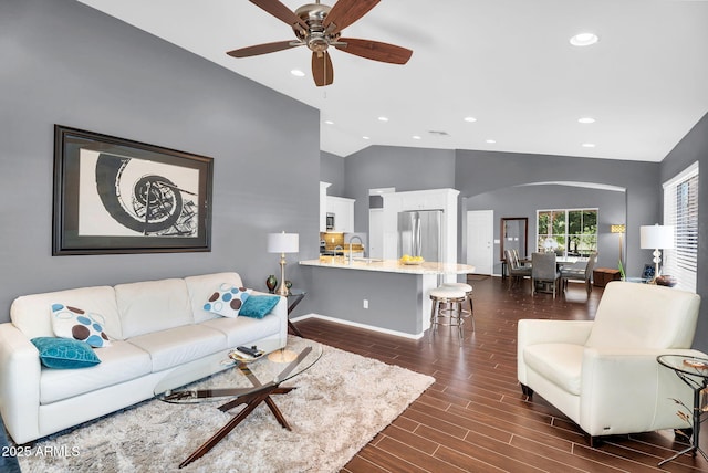 living area featuring arched walkways, dark wood-type flooring, recessed lighting, ceiling fan, and baseboards