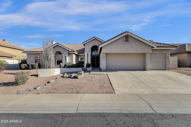 view of front of property featuring an attached garage, a tile roof, concrete driveway, and stucco siding