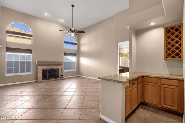 kitchen with a fireplace, ceiling fan, a high ceiling, and a wealth of natural light