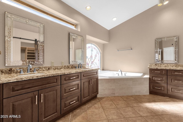 bathroom with tile patterned flooring, tiled tub, vanity, and lofted ceiling