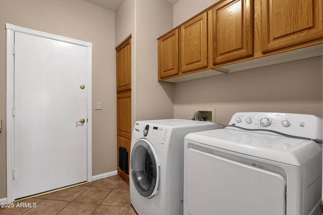 laundry room with washing machine and clothes dryer, light tile patterned floors, and cabinets