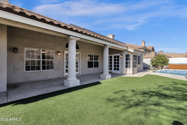 rear view of house featuring a patio area, a fenced in pool, and a lawn