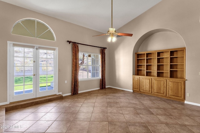 tiled empty room with ceiling fan, high vaulted ceiling, and french doors