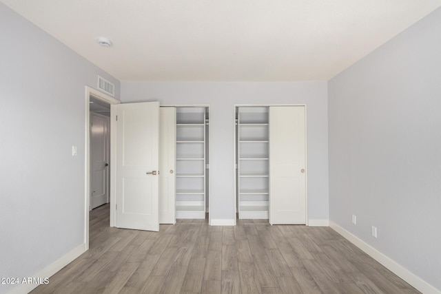 4302 N 80th Ln, Phoenix, AZ 85033 - unfurnished bedroom with multiple closets, baseboards, and wood finished floors