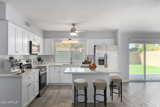 4302 N 80th Ln, Phoenix, AZ 85033 - kitchen with appliances with stainless steel finishes, a sink, a kitchen breakfast bar, light wood finished floors, and a center island