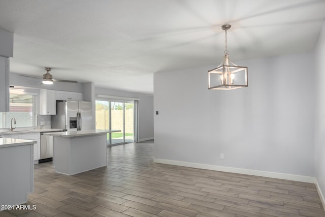 4302 N 80th Ln, Phoenix, AZ 85033 - kitchen featuring appliances with stainless steel finishes, light wood-style flooring, a kitchen island, open floor plan, and light countertops