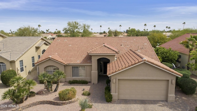 mediterranean / spanish-style house with an attached garage, a tile roof, driveway, and stucco siding