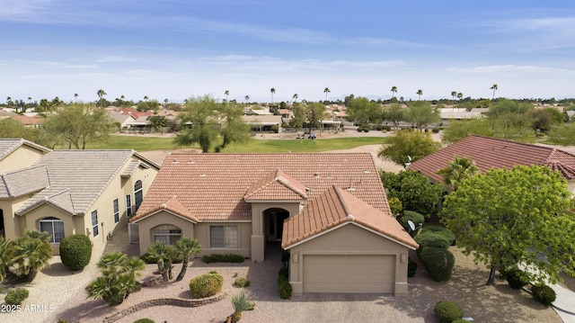 view of front of property with a residential view, a tiled roof, a garage, stucco siding, and decorative driveway