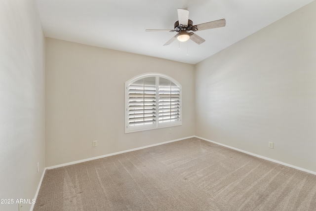 carpeted spare room featuring a ceiling fan and baseboards