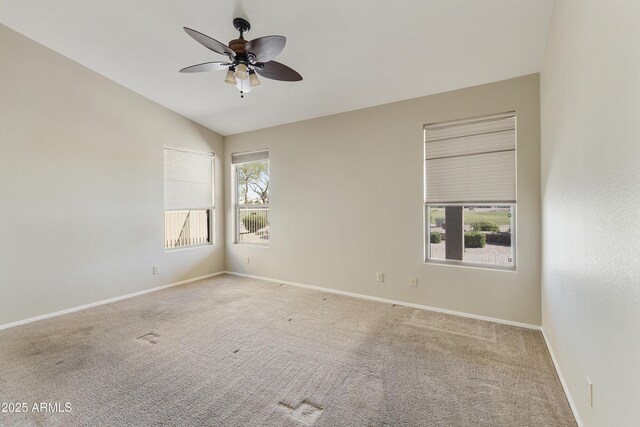 carpeted empty room featuring baseboards, lofted ceiling, a ceiling fan, and plenty of natural light