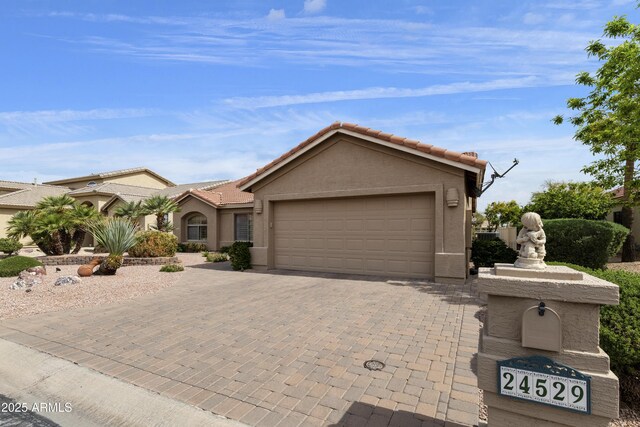 view of front facade featuring stucco siding, an attached garage, decorative driveway, and a tile roof